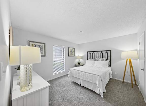 A bedroom with a bed, nightstand, and two lamps.