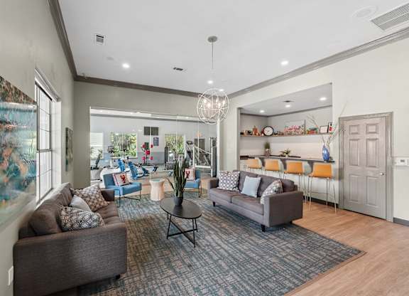 A living room with a grey couch and a painting on the wall.