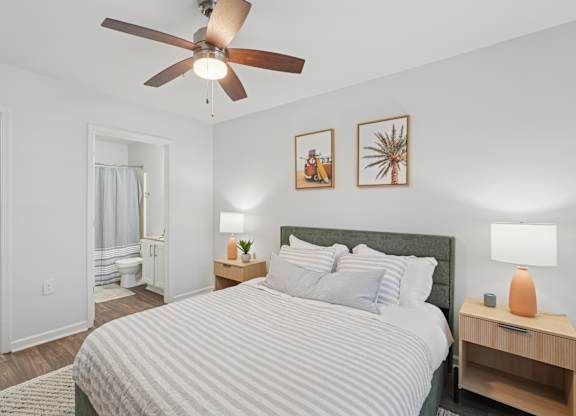 A bedroom with a bed, nightstand, and two wall art pieces.