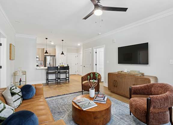 A living room with a brown couch, a brown chair, a coffee table, and a ceiling fan at Union Eleven Apartments, Georgia
