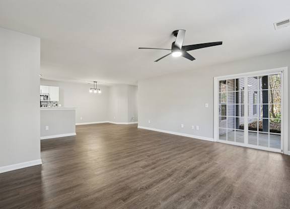 A room with a ceiling fan and wooden flooring.