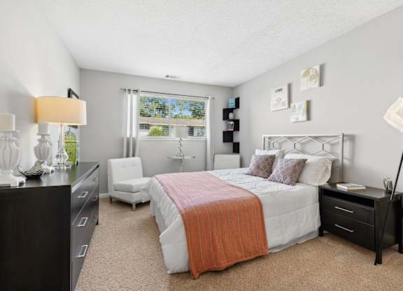 A bedroom with a bed, nightstand, and chair.