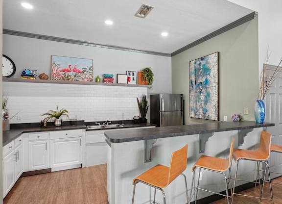 A kitchen with a bar and chairs.