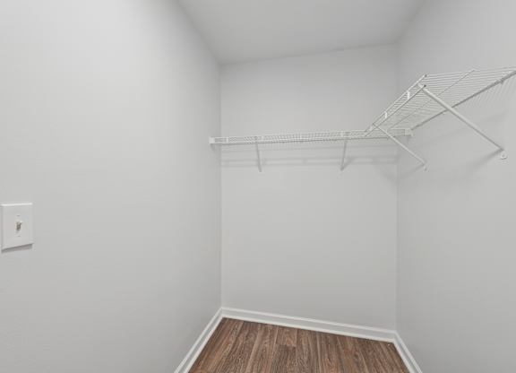 A white wall with a light switch and a white shelf.