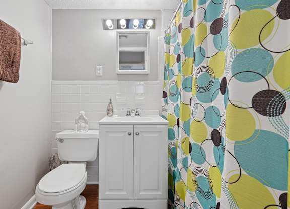 A bathroom with a toilet, sink, and shower curtain.