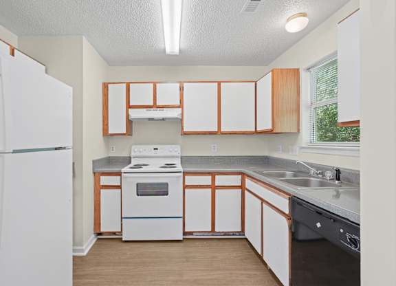 A kitchen with a white refrigerator and wooden cabinets.