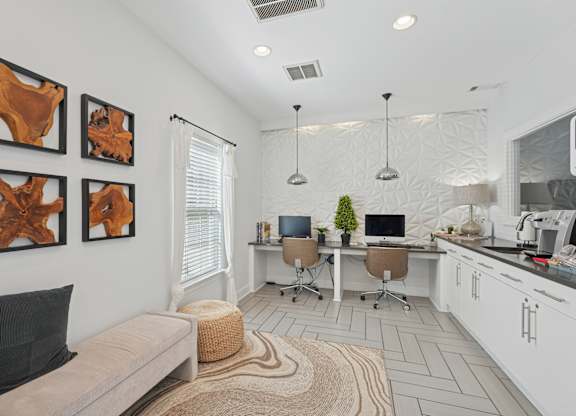 A modern living room with a couch, a desk with a computer, and three abstract paintings on the wall.