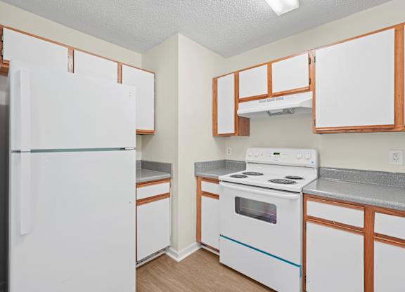 A white refrigerator is in a kitchen with wooden cabinets.