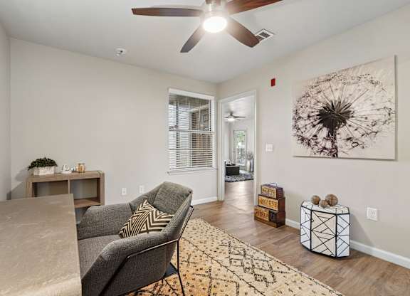 A living room with a grey couch, a rug, and a ceiling fan.