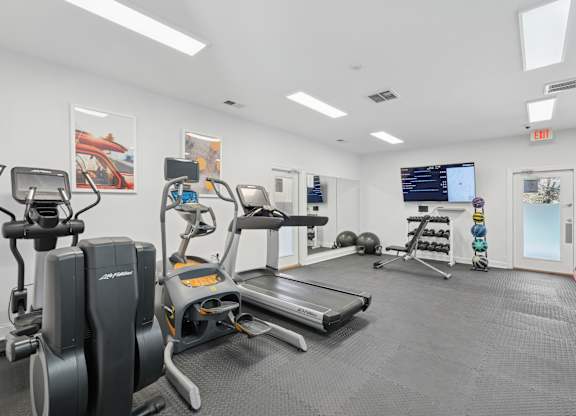 A gym with a treadmill, elliptical machines, and other exercise equipment.