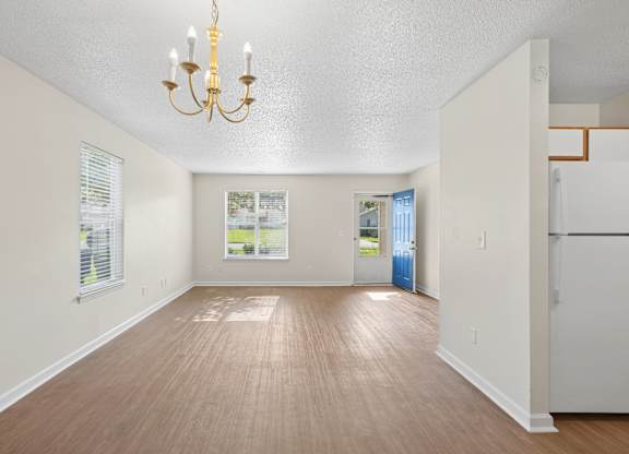 A room with a chandelier and wooden flooring.