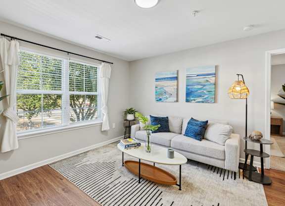 A living room with a white couch, a coffee table, and two paintings on the wall.