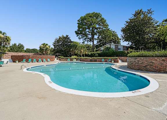 A large outdoor swimming pool with a white border and a white concrete edge.