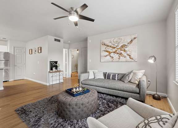 A living room with a grey couch and a round ottoman.