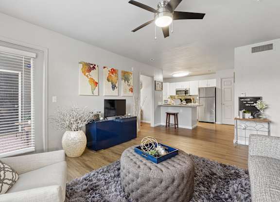 A living room with a grey ottoman and a white couch.