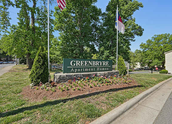 Community entrance sign with flags and stone base at Greenbryre Apartments, Charlotte, NC 28205