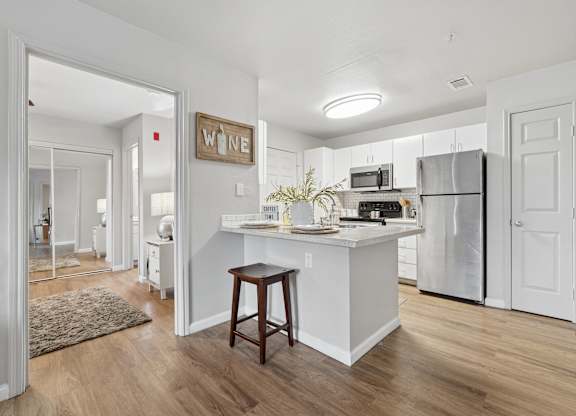 A kitchen with a white island and a wooden stool.