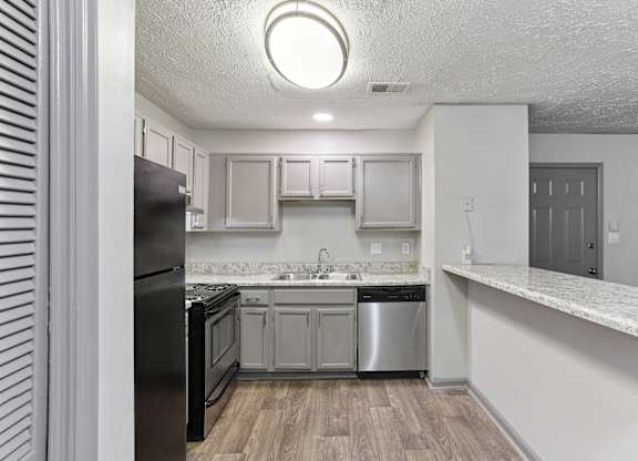 A kitchen with a black refrigerator, white cabinets, and a marble countertop.at Brighton Way, Georgia
