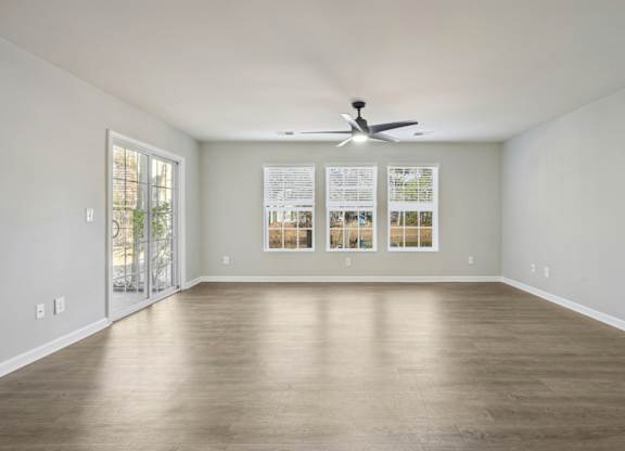 A spacious room with a ceiling fan and a wall-mounted light switch.