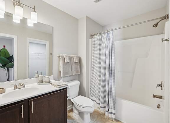 A bathroom with a white toilet, sink, and shower.