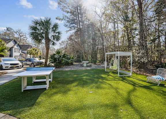 A backyard with a white table and a swing set.