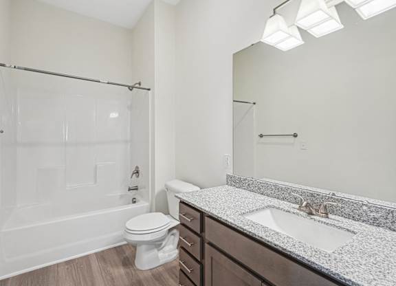 A white bathroom with a toilet, sink, and shower.at The Parker Leland, North Carolina, 28451