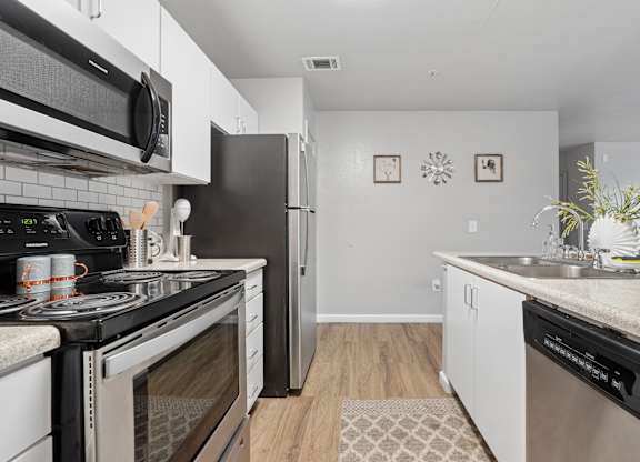 A kitchen with black appliances and white cabinets.