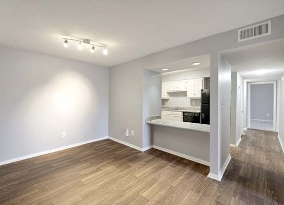 Living room and kitchen of an apartment with wood flooring and white walls  at Governors House, Huntsville