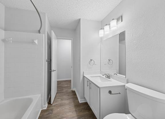 A white bathroom with a tub, sink, and mirror.