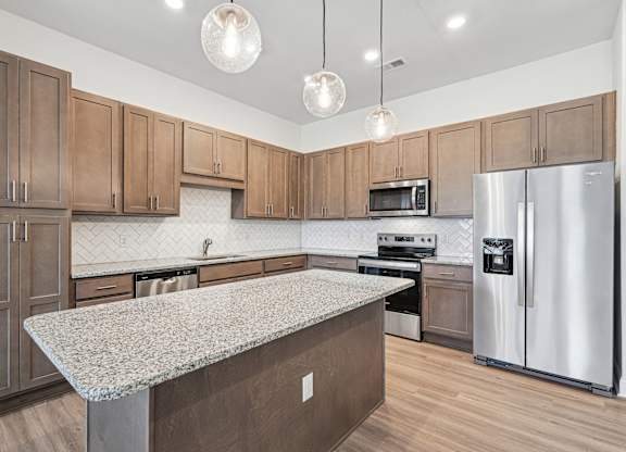 A kitchen with wooden cabinets and a granite countertop.at The Parker Leland, North Carolina