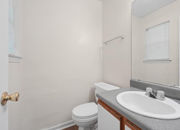 A bathroom with a toilet, sink, and mirror.