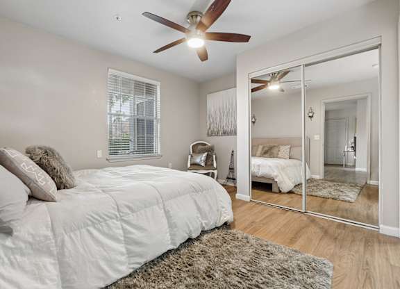 A bedroom with a large bed and a ceiling fan.