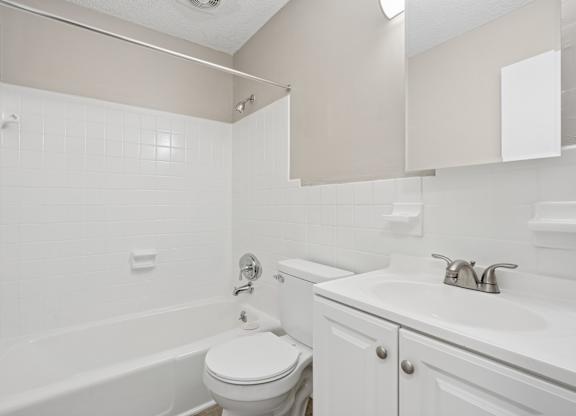 A white bathroom with a toilet, sink, and bathtub.