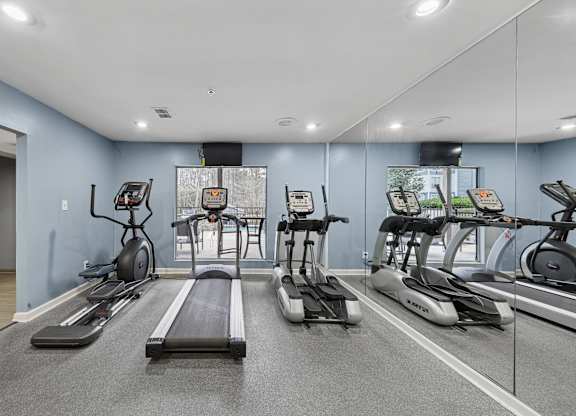 A spacious gym with treadmills, elliptical machines, and stationary bikes.