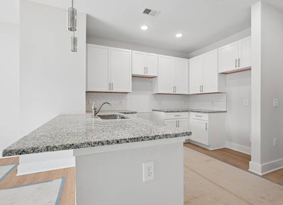 A kitchen with white cabinets and a granite countertop.