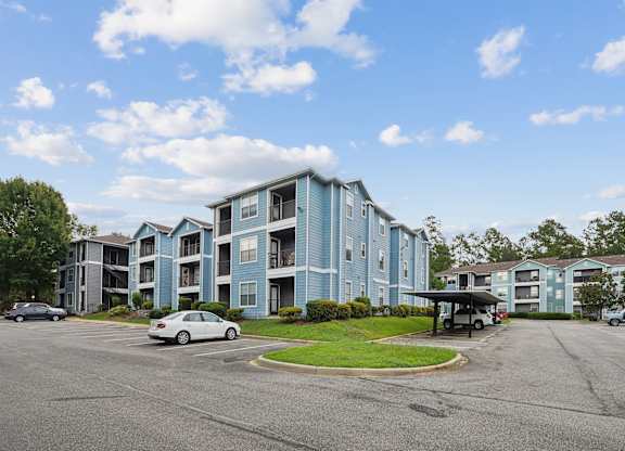 A large apartment complex with a parking lot in front.