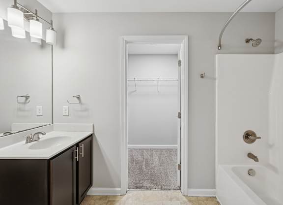 A bathroom with a white tub, sink, and mirror.