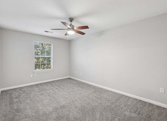 A room with a ceiling fan and carpeted floor.