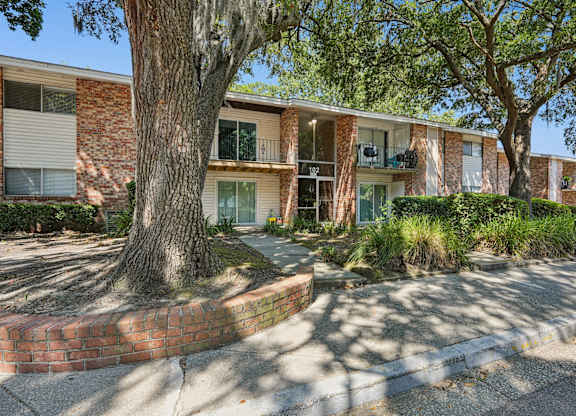 A tree in front of a building with a brick wall.
