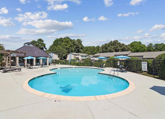 A large outdoor swimming pool surrounded by a fence and trees at The Taylor, Marietta, GA.