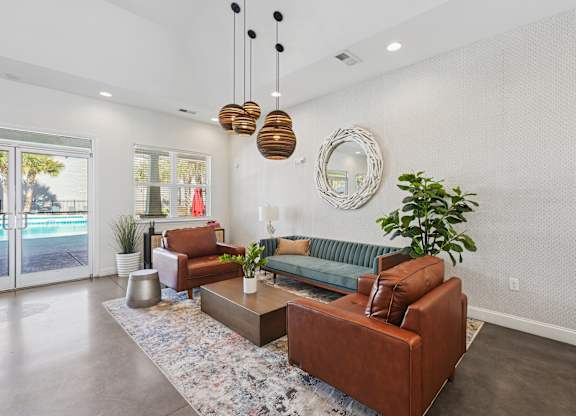 A living room with a brown couch, a mirror, and a plant.