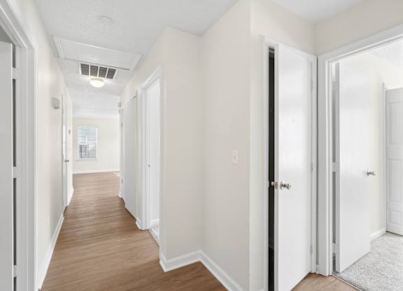 A long hallway with white walls and wood floors.