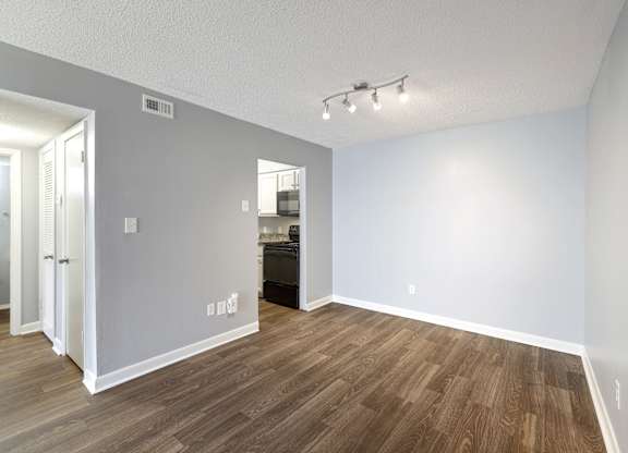 an empty living room with wood flooring and a door to a kitchen  at Governors House, Huntsville, 35805