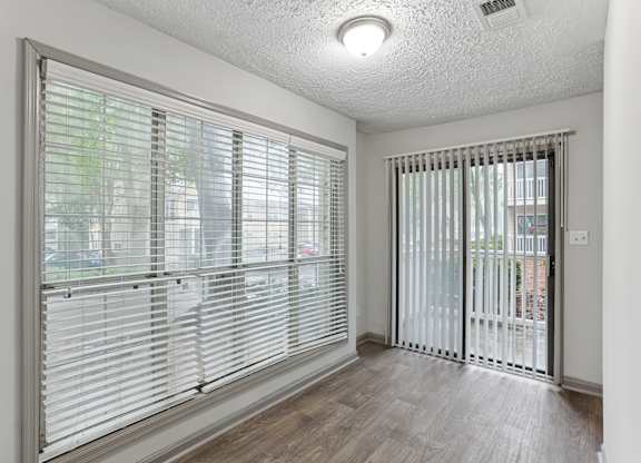 A room with a sliding glass door and a window with blinds.at Brighton Way, Georgia