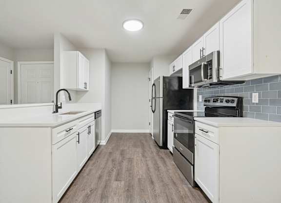 A modern kitchen with white cabinets and a black refrigerator.