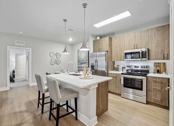 A modern kitchen with a dining table and chairs.at The Exchange at Crestview Apartments, Crestview, Florida