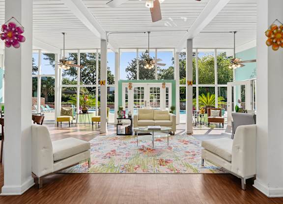 A white room with a floral rug and two white chairs.