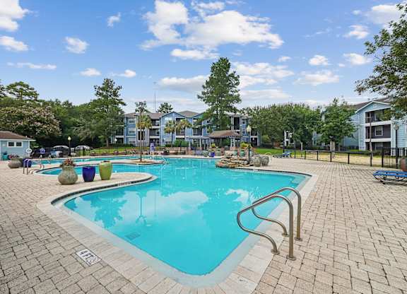 A large swimming pool surrounded by a brick patio.