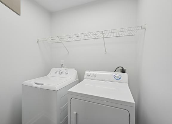 Two white front loading washing machines in a laundry room.