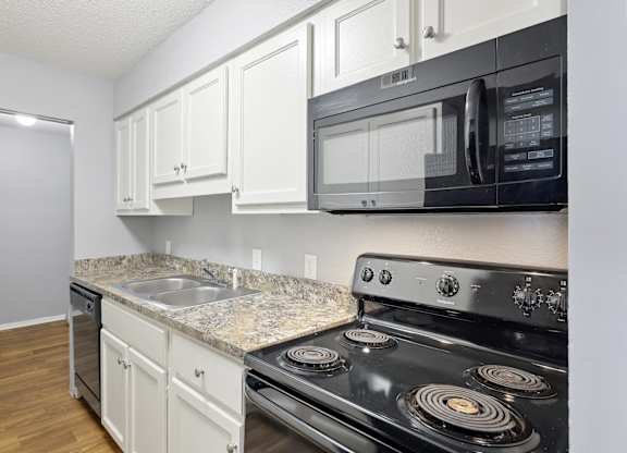 Kitchen with white cabinets and black appliances and a sink  at Governors House, Huntsville, Alabama